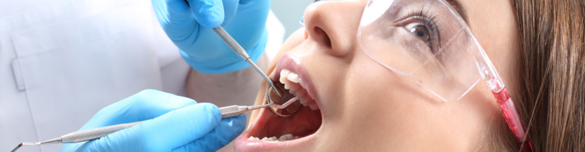 A dentist wearing blue gloves working on a patient.